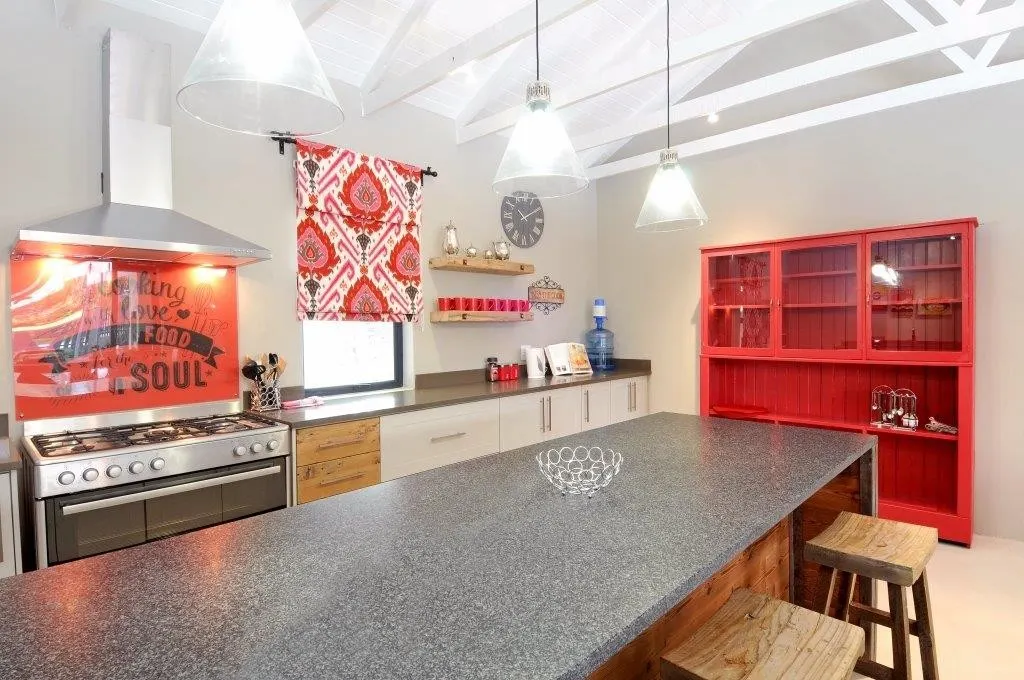 A dark stone island in a kitchen with red accents