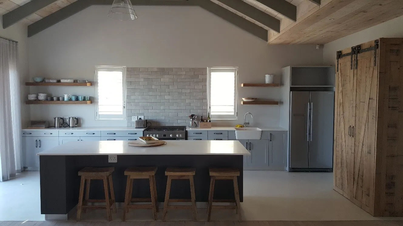 A broad island in a kitchen with exposed roof beams