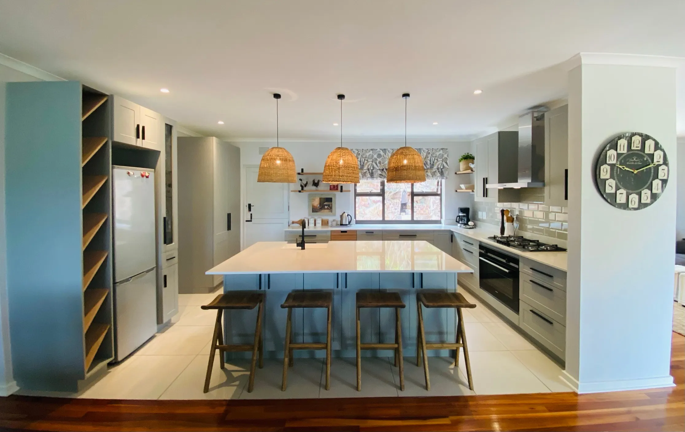 A pale island with woven pendants and oak cabinetry