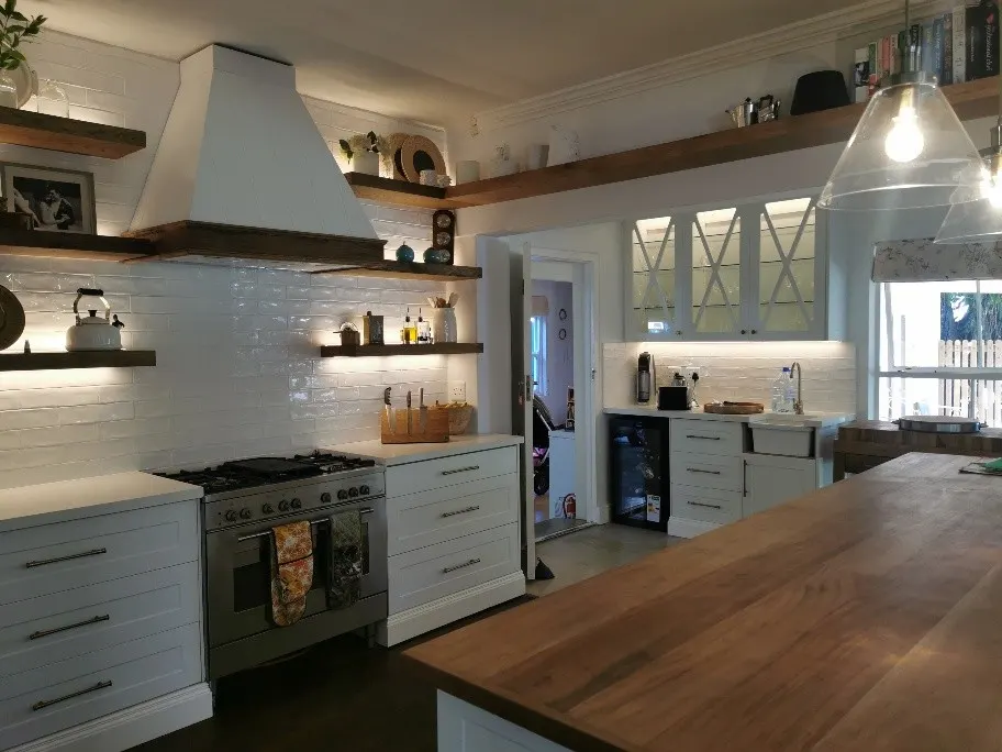 Pale worktops beneath open timber shelving