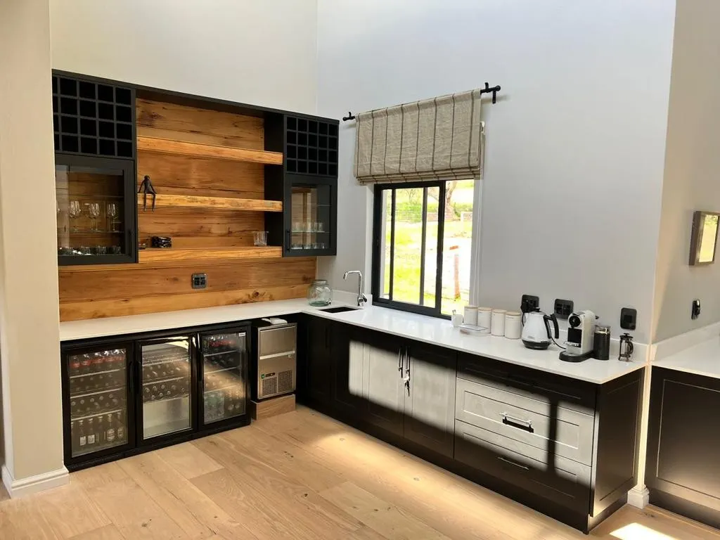 A stone counter with a sink and wine fridges in a home bar